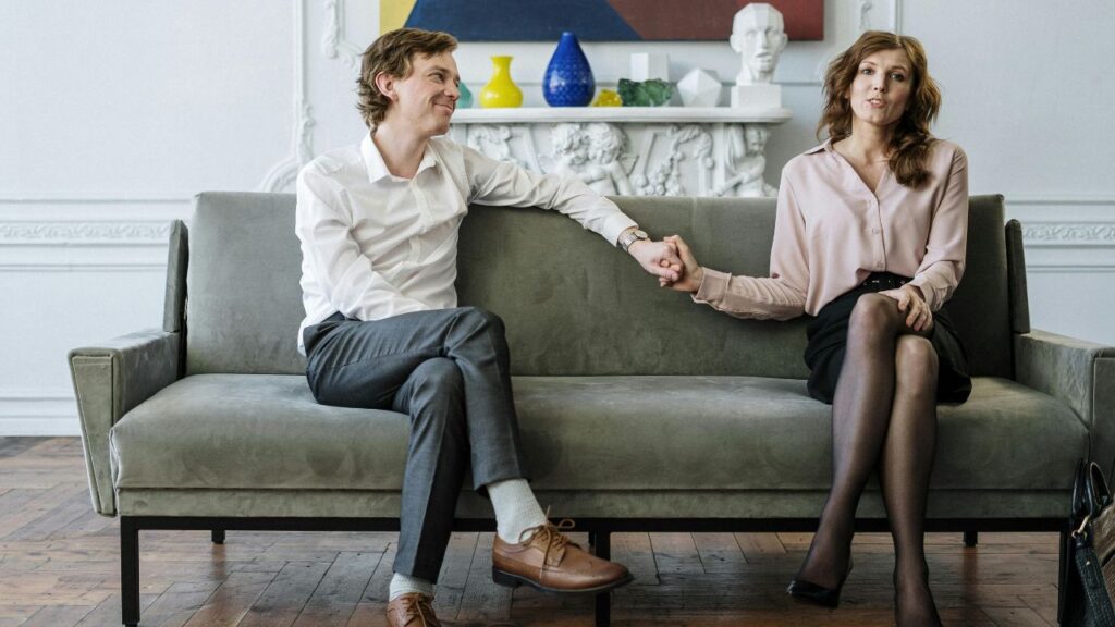Woman in White Long Sleeve Shirt Sitting on Gray Couch