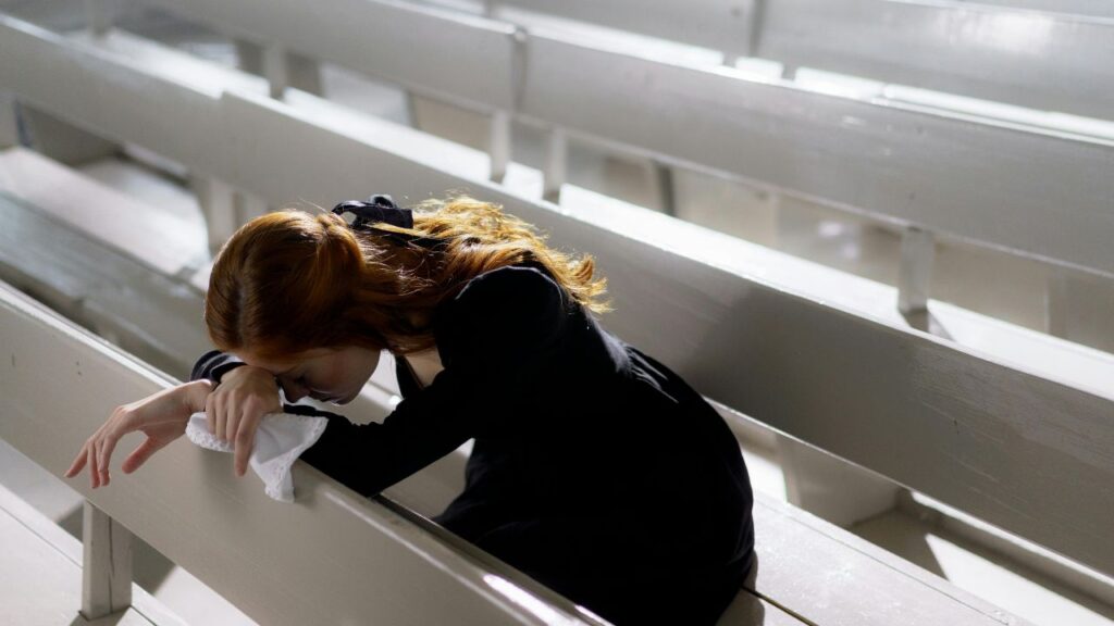 A Woman in Black Long Sleeve Shirt Sitting Alone on Wooden PewA Woman in Black Long Sleeve Shirt Sitting Alone on Wooden Pew