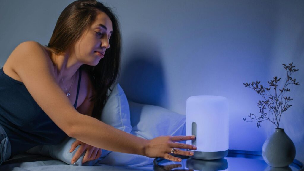 A Woman Lying on the Bed Turning on the Lamp