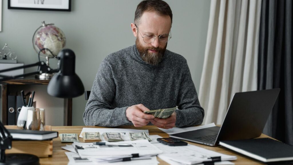 A Man in Gray Long Sleeves Shirt Counting Cash Money