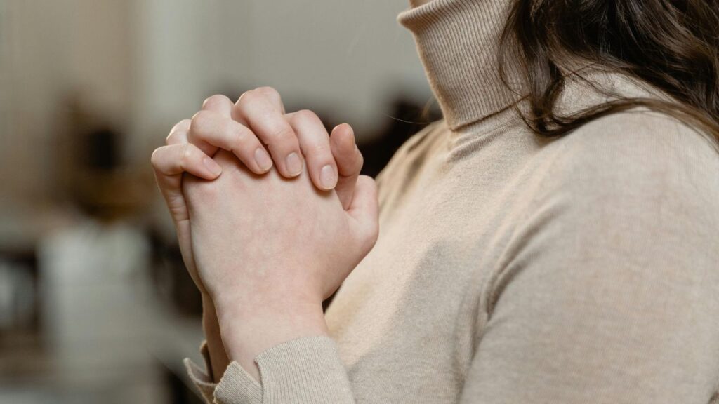 Woman in Brown Turtle Neck Shirt with Hands Clasped