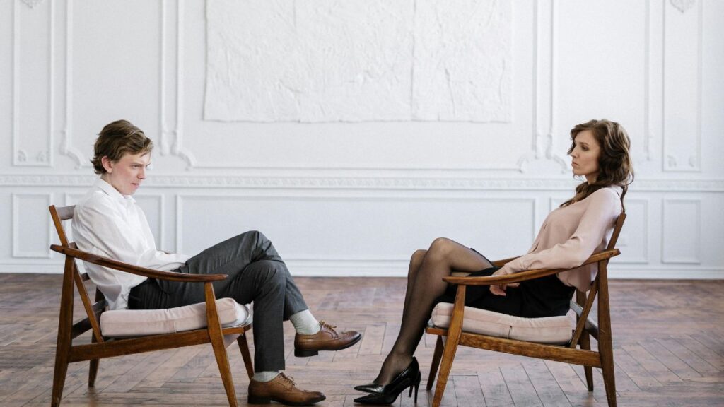 Woman in Gray Pants Sitting on Brown Wooden Armchair
