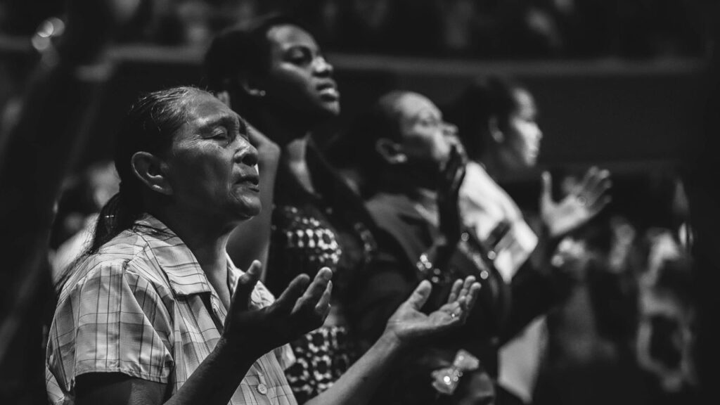 Grayscale Photo of People Raising Hands