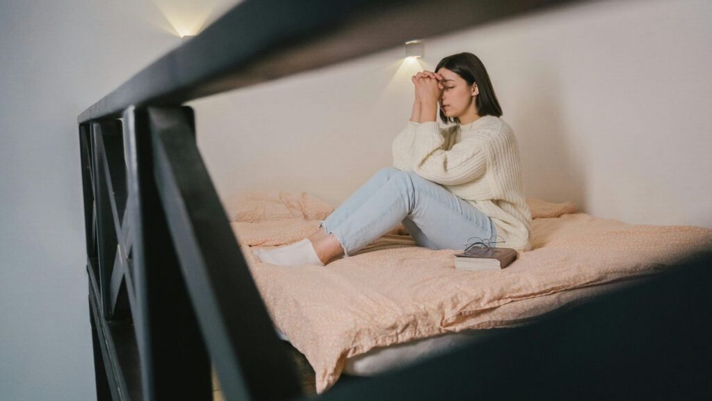 Woman in White Sweater and Blue Denim Jeans Sitting on Bed