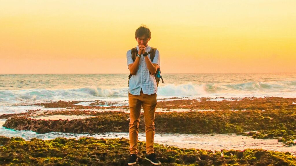 Man Standing on Rocks Near Beach during Golden Hour
