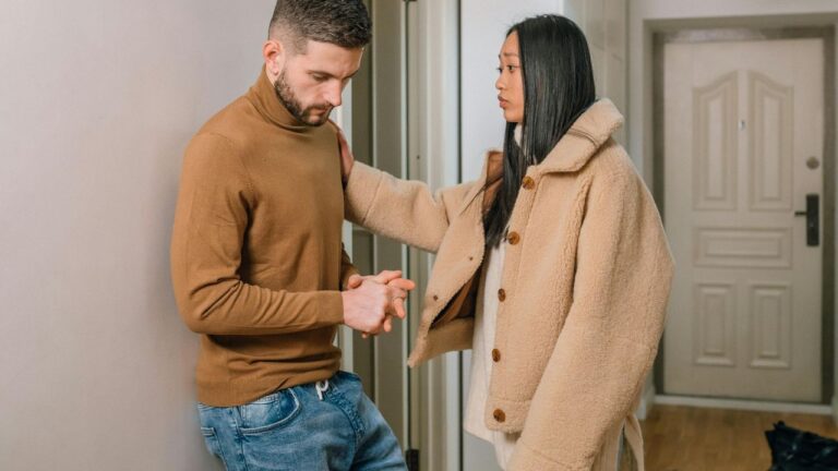 A Sad Woman Standing in Front of a Man Leaning on the Wall