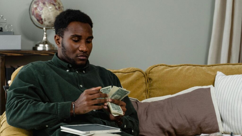 A Man in Green Long Sleeve Button Up Shirt Counting Money