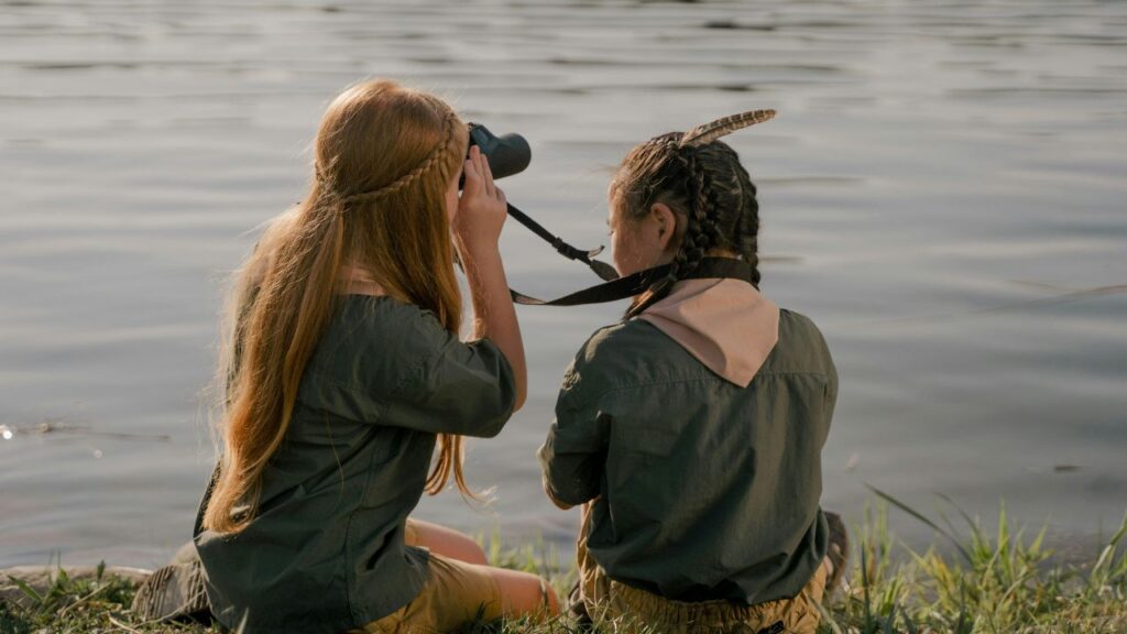 Two Girls Sitting on the Grass near Lake