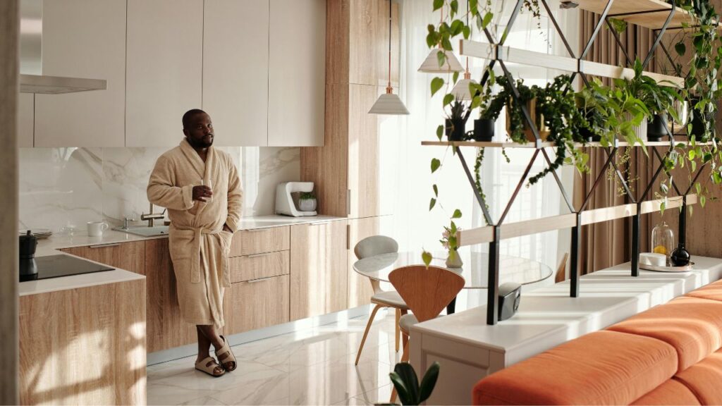 Wear in Bathrobe Man Standing in Kitchen with Glass in Hand