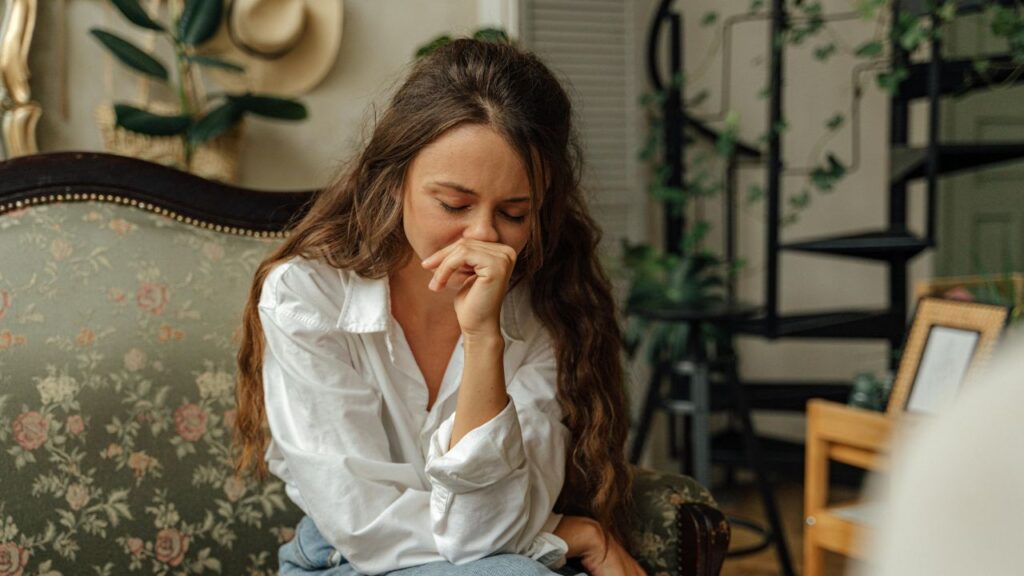 Woman in White Dress Shirt and Blue Denim Jeans Sitting on Brown Floral Sofa
