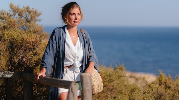Beautiful woman walking in the grass along the coves of a beach,