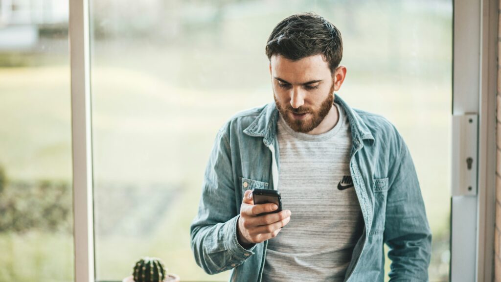 man holding a smartphone near the window