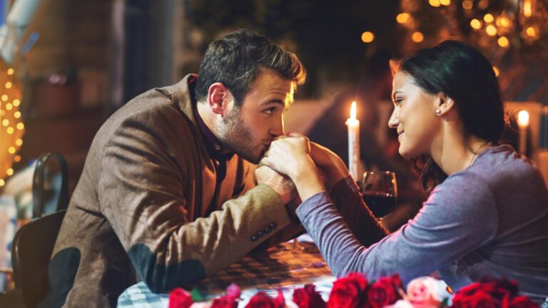 Couple dinner and date in restaurant for romance with hand kiss candle or commitment to relationship at night Man woman and anniversary celebration on valentines day with happiness or fine dining
