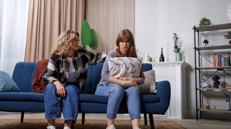 Mature woman sitting on a sofa is trying to calm her daughter who is suffering from depression I'm sorry I didn't mean to offend you