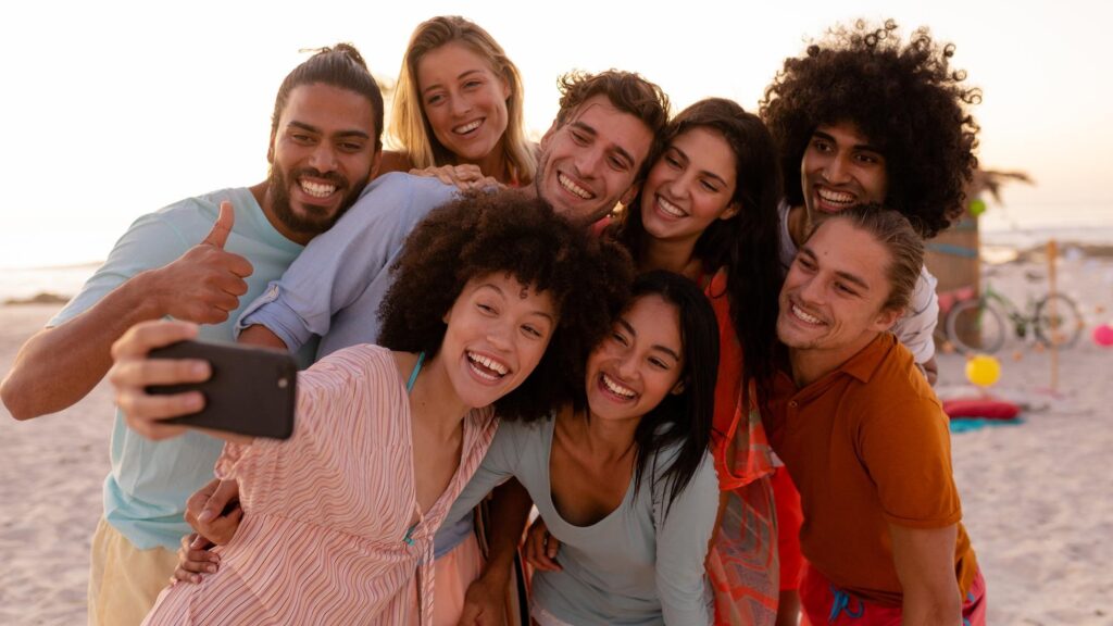 A multi-ethnic group of friends enjoying their time together, holding a smartphone, taking a selfie together