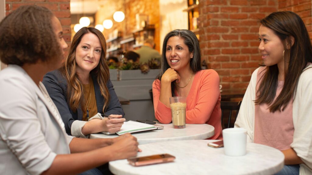 four women chatting at cafe table