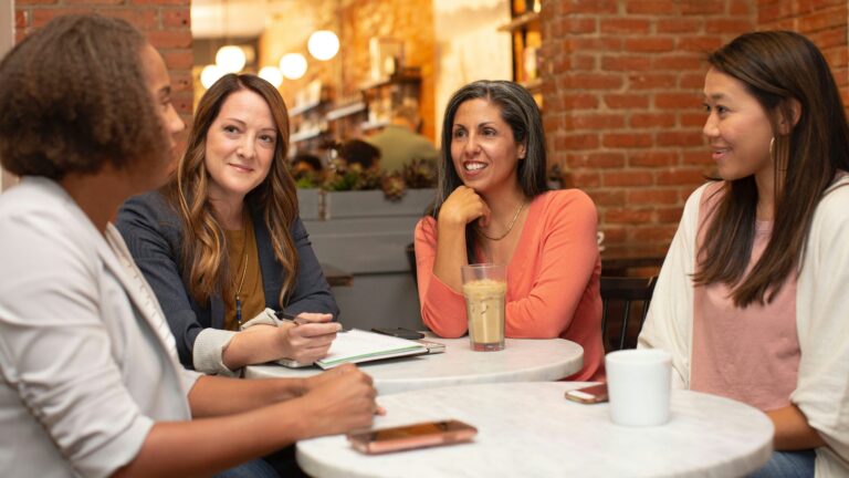 four women chatting at cafe table