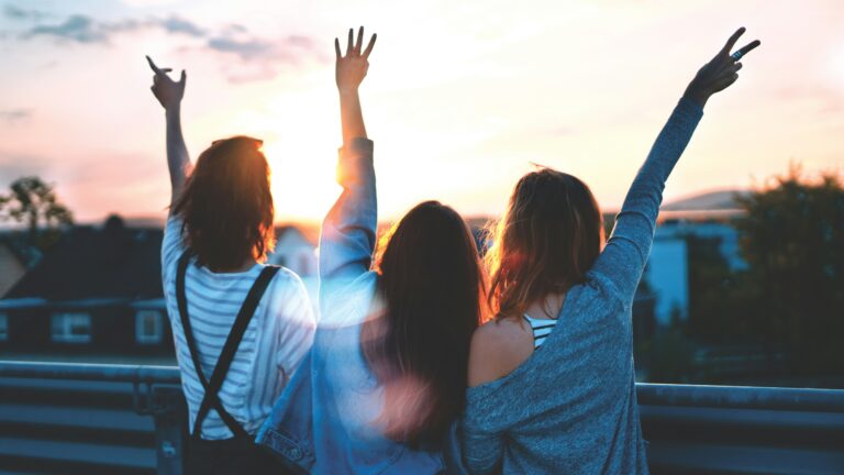 photo of three women lifting there hands