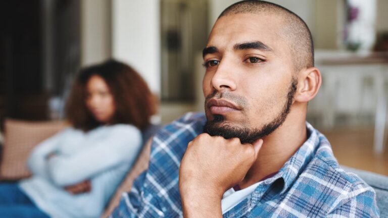 Unhappy couple after argument with a frustrated upset and sad husband looking away from his wife at home Depressed and distant boyfriend sitting on the couch after fighting with his girlfriend