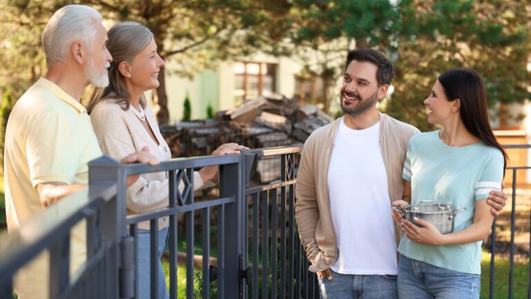 Friendly relationship with neighbours Young family talking to elderly couple near fence outdoors