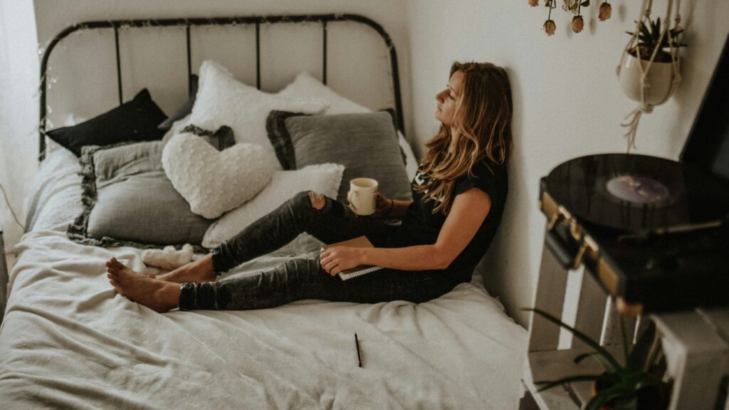 woman leaning on wall while sitting on bed