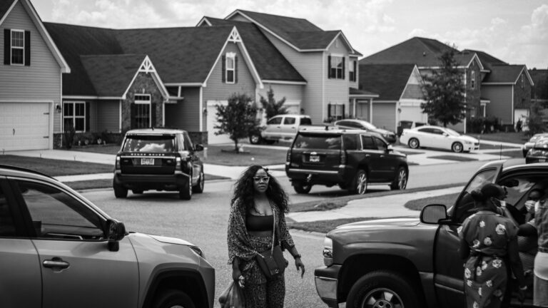 grayscale photo of woman standing near car