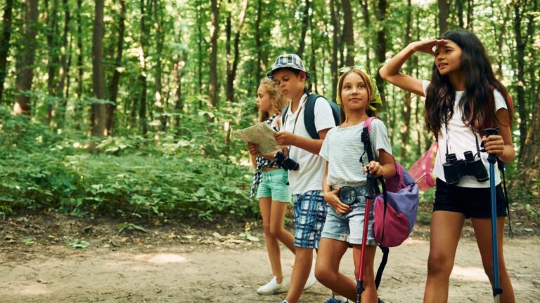 Front view Kids strolling in the forest with travel equipment