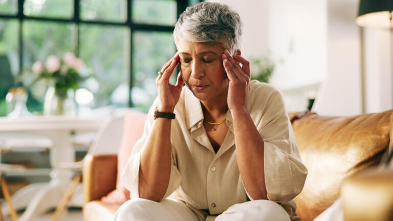 Headache stress and senior woman on sofa in home with fatigue tension or brain fog in living room Burnout migraine and female person with discomfort for dizziness exhaustion or vertigo in house