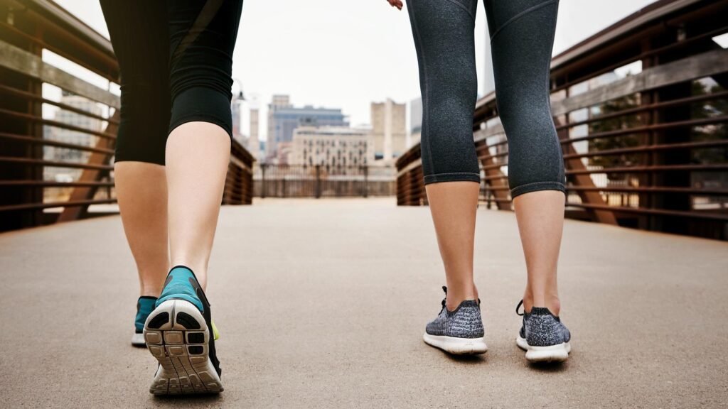 Women legs and walking with shoes on city bridge for workout exercise or training together Active female people or sneakers with movement or mobility for cardio health or fitness in urban town