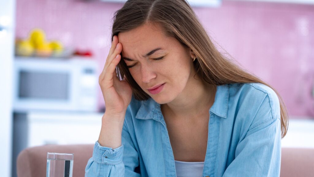 Sad stressed unhappy woman suffering from strong headache at home. Feeling migraine and physical fatigue