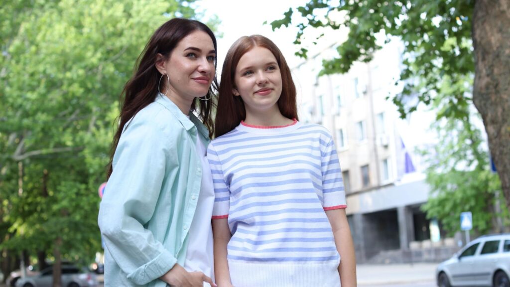 Beautiful mother and her teenage daughter on city street