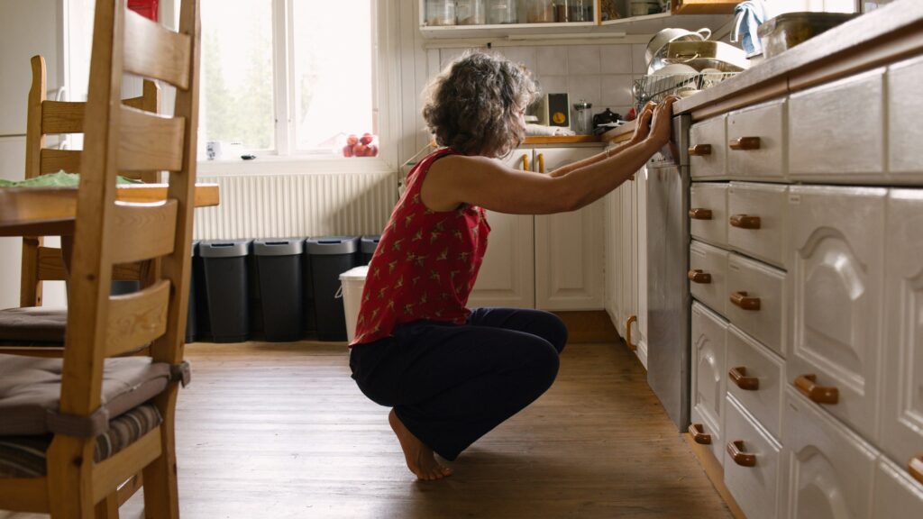 A woman kneeling on the floor in a kitchen