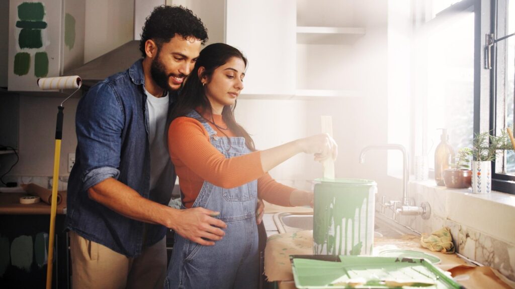 Diy hug and painting with couple in kitchen of apartment together for home improvement or renovation Maintenance mixing and project with people embracing in new house for remodeling or restoration
