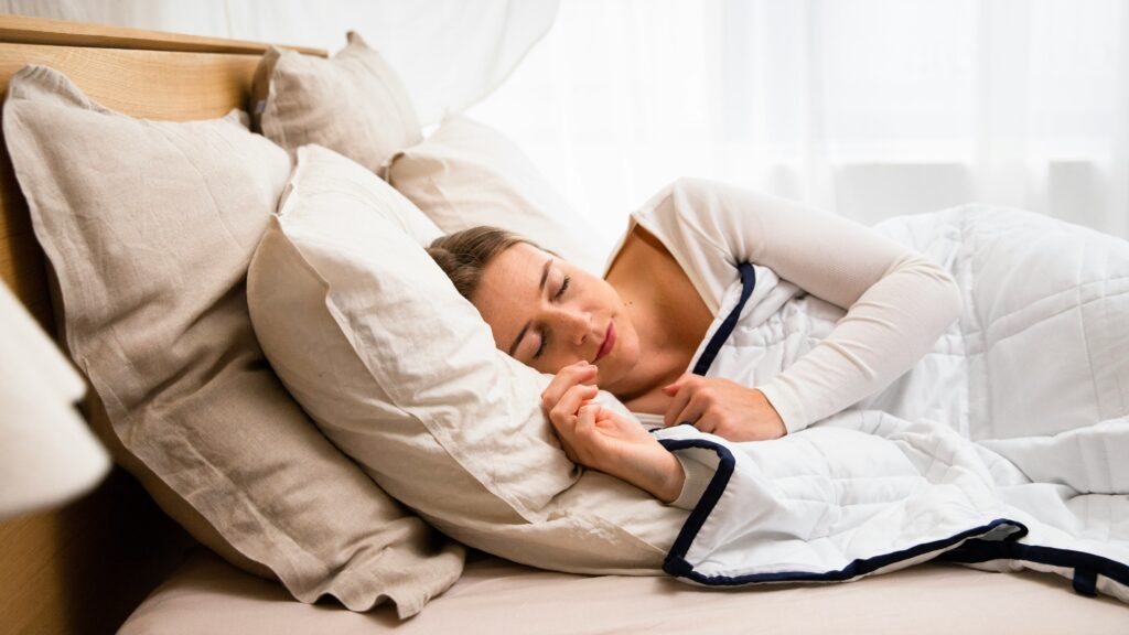 a woman sleeping in a bed with a white comforter
