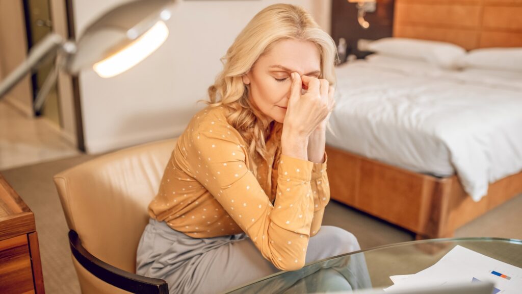 Headache. Blonde stylish businesswoman looking tired after a hard working day