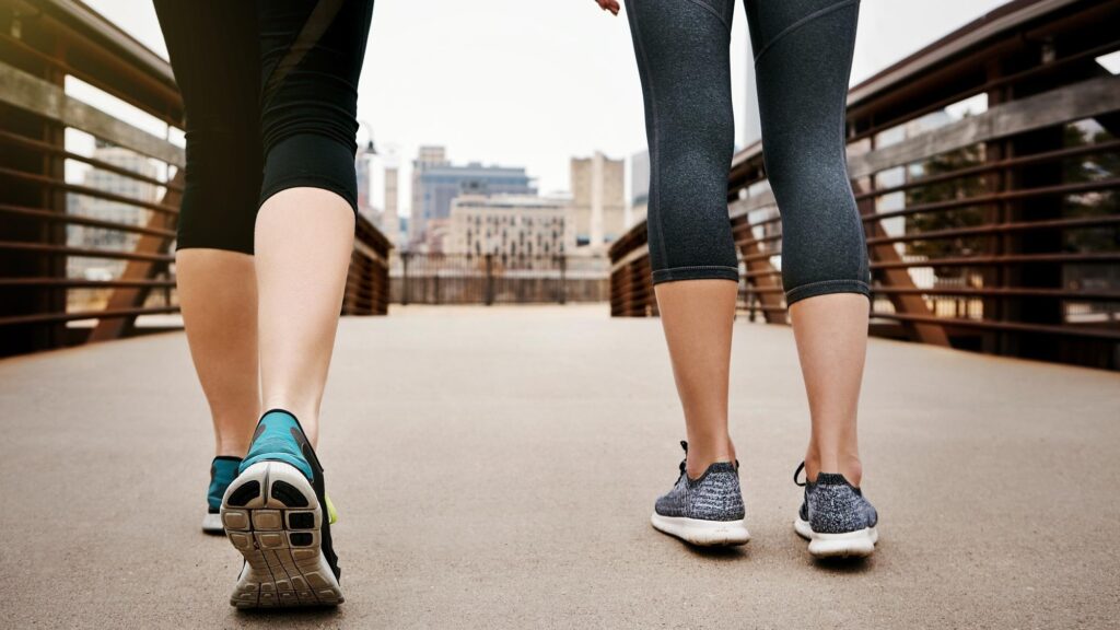 Women legs and walking with shoes on city bridge for workout exercise or training together Active female people or sneakers with movement or mobility for cardio health or fitness in urban town