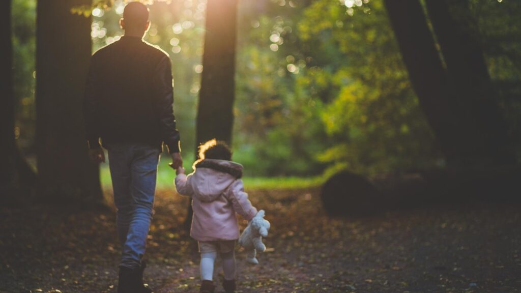 a father and daughter walking in the woods
