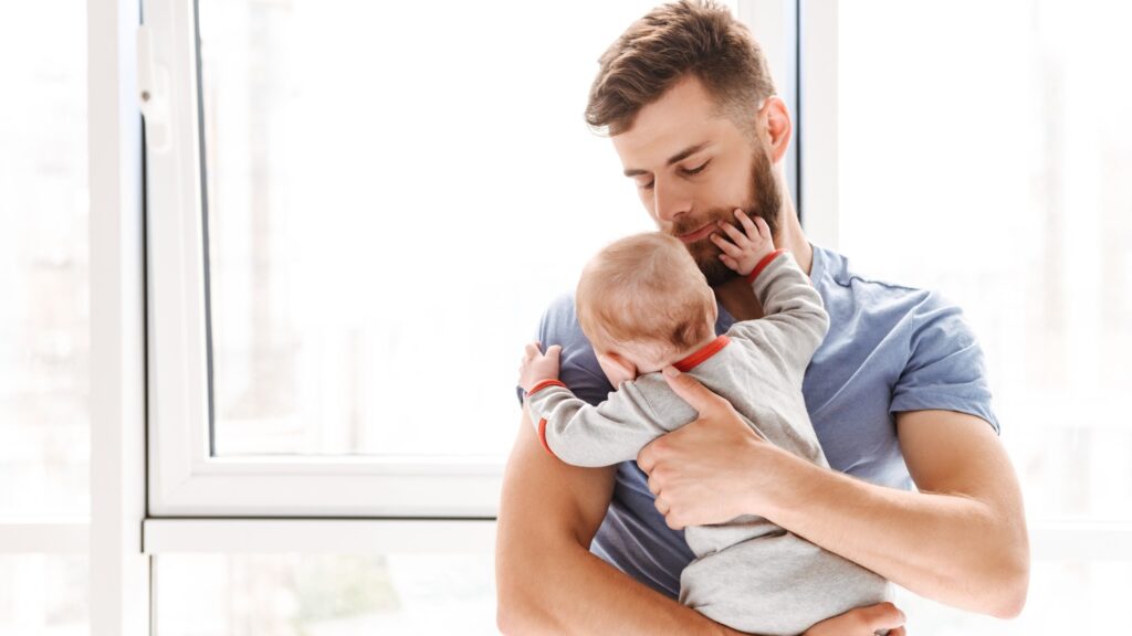 Handsome young man father dad holding in hands his little baby