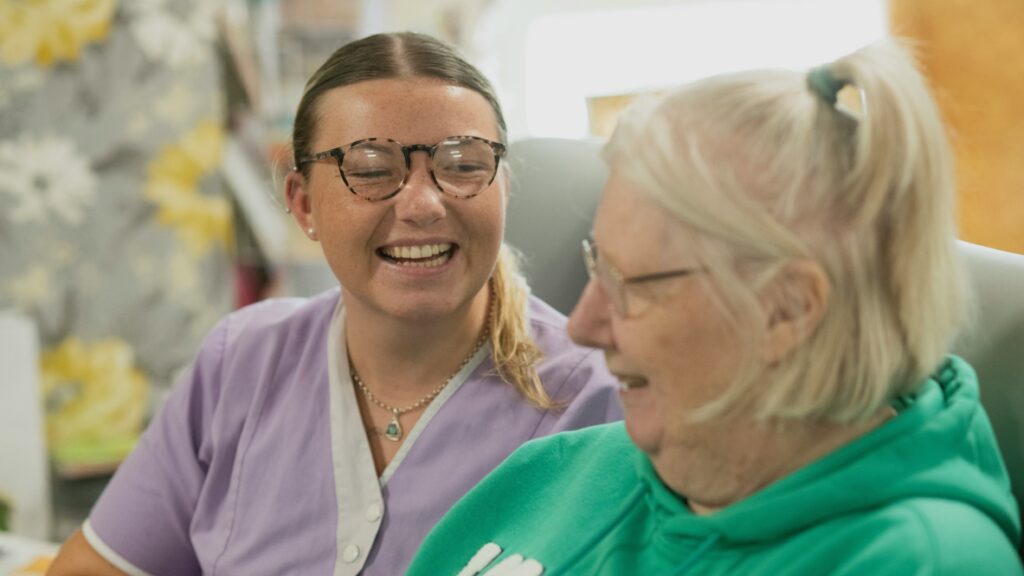Two women laughing together indoors.