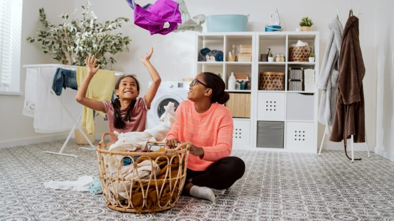Daughter is fooling around playing by mother tossing her clothes high above head