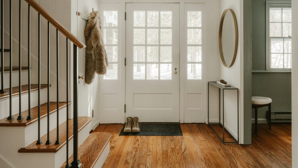 A cozy entryway with wooden stairs and a glass door.