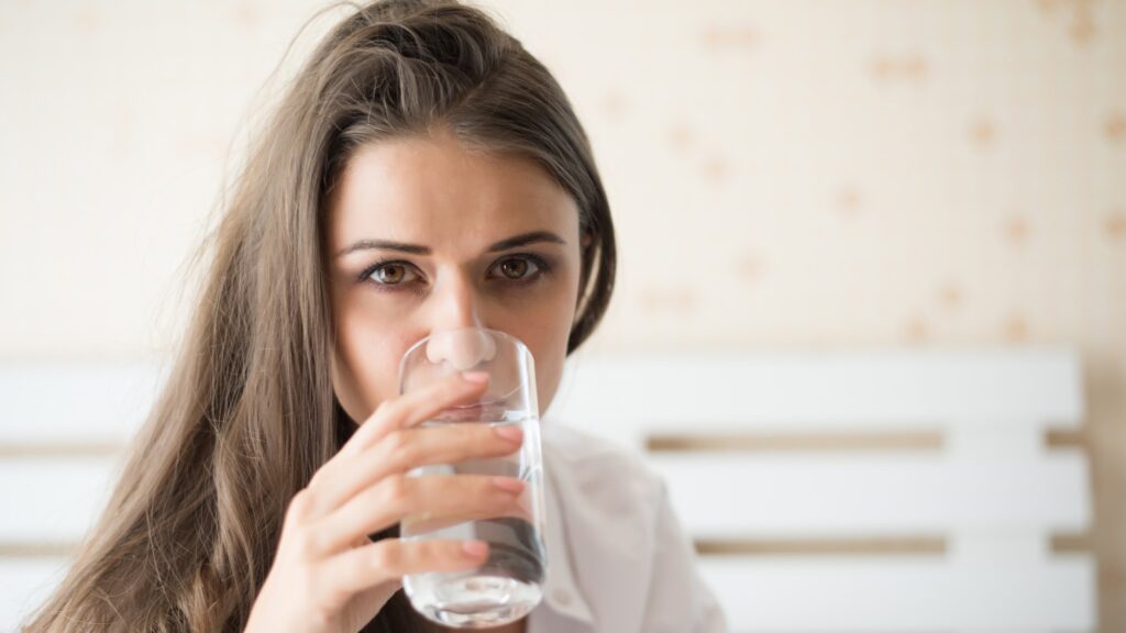 Beautiful woman drinking fresh water in the bed at the morning