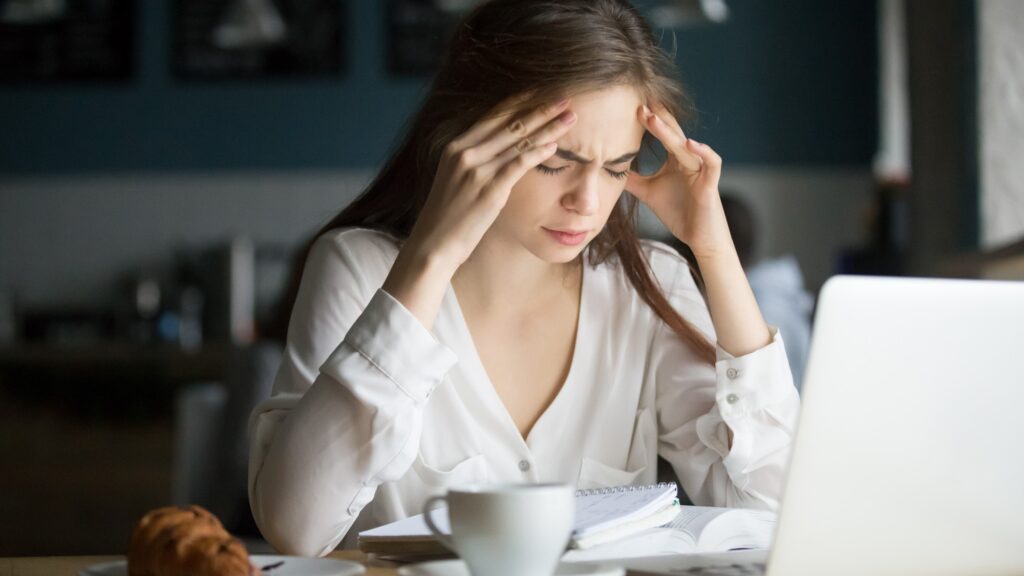 Nervous stressed female student feeling headache studying in cafe