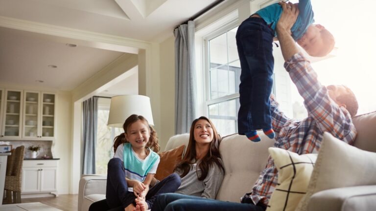 Playful smile and support with family on sofa for bonding love and comfortable together Happiness calm and relax with parents and children in living room of home for peace trust and care