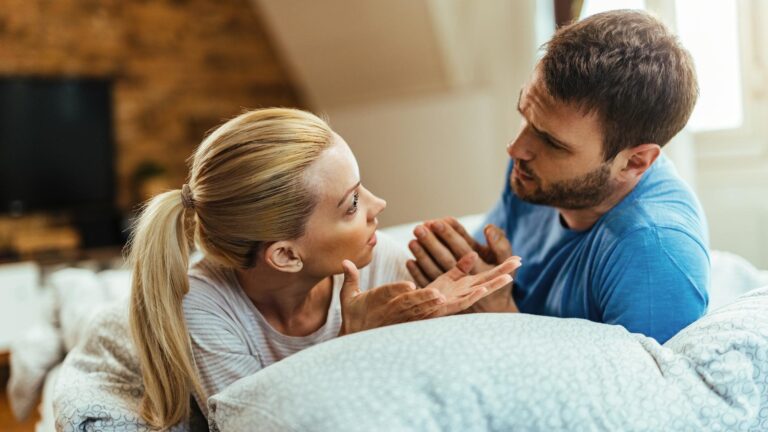 Young couple talking while having relationship problems in bedroom