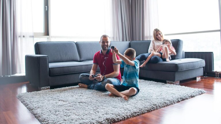 Happy family. Father, mother and children playing a video game Father and son playing video games together on the floor