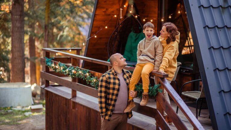 Happy family of travelers in the forest in the mountains near the wooden chalet house