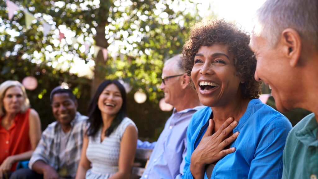 Group Of Mature Friends Socializing In Backyard Together
