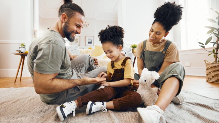 Happy family bond and relax on a floor with care fun and hand game in a home Love carpet and boy child with interracial parents in living room playing learning and development together in house