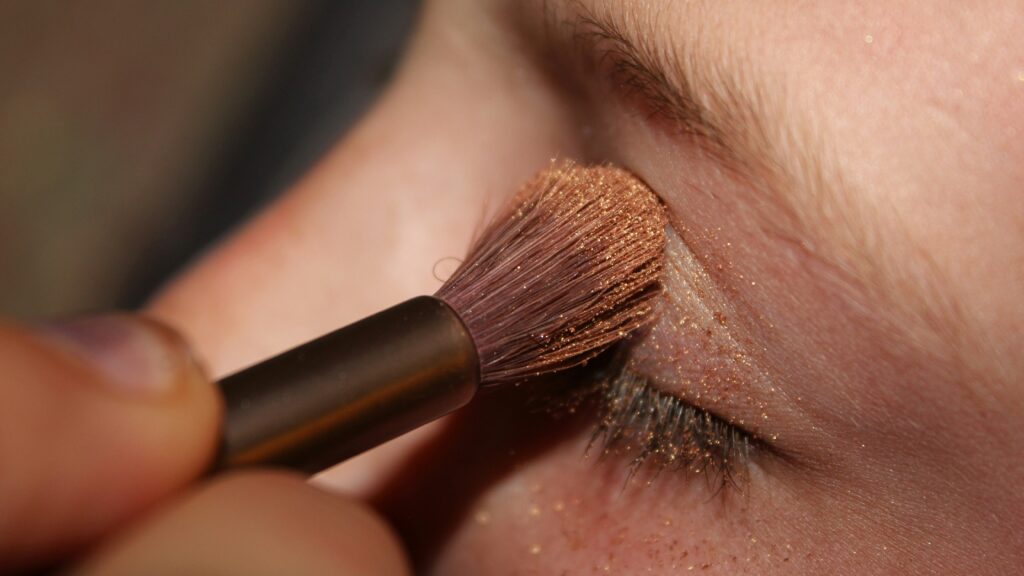 woman applying brown glittered eyeshadow